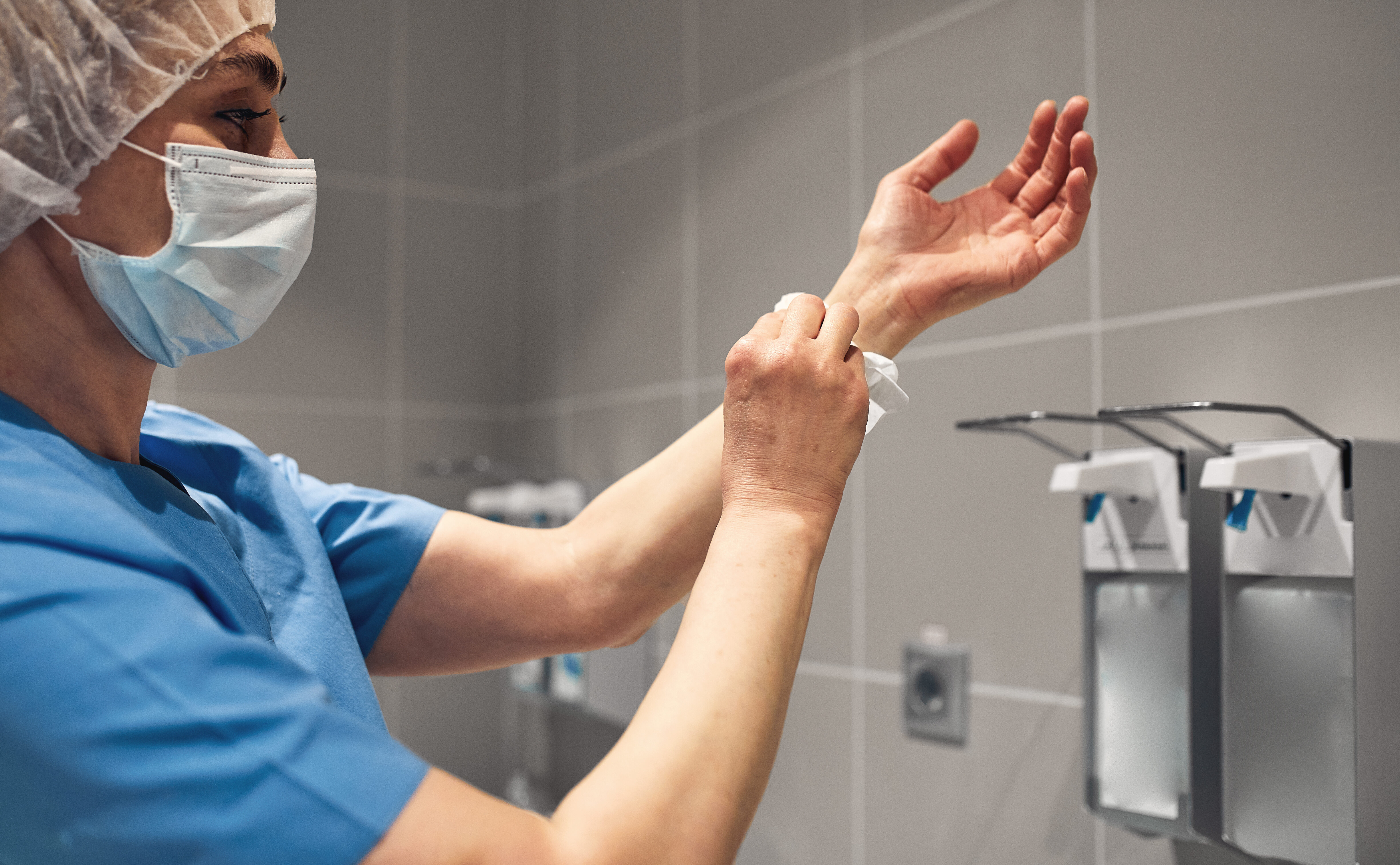Close-up of a doctor washing his hands using a disinfectant dispenser.