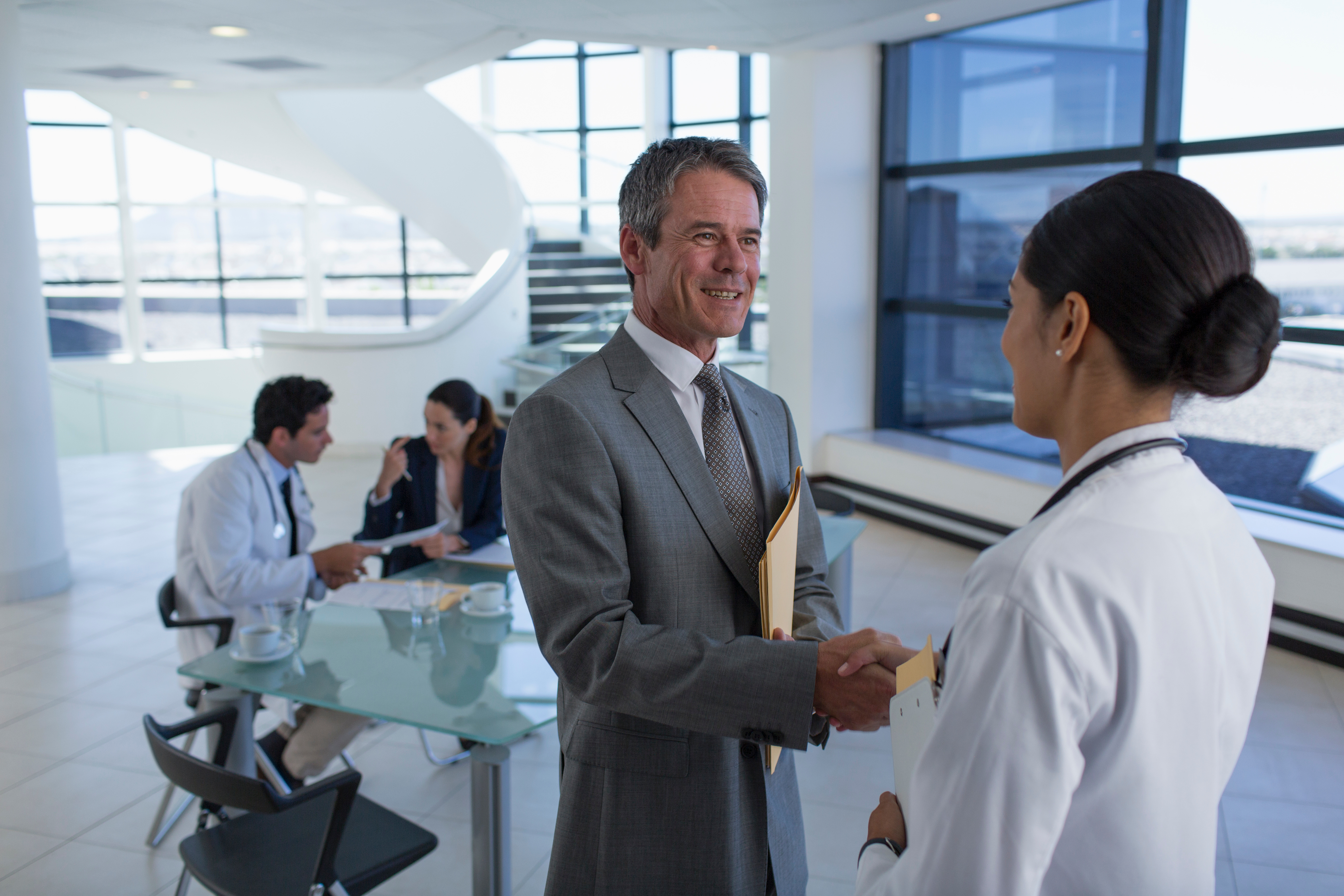 Hospital administrator shaking hands with doctor in meeting